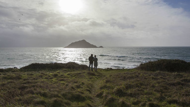 A couple hand in hand looking out to sea at Wembury Point, Devon